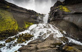 Быстрый горный водопад под серым небом