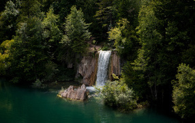 The waterfall flows from the cliff into the cold lake