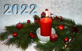 Candle and fir branch with decorations for new year 2022