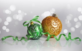 Два красивых елочных шарика с ленточкой на сером фоне 