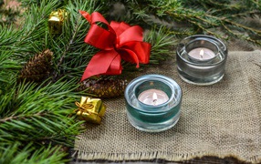 Две зажженные свечи, еловая ветка и красный бант на рождество 