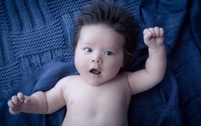 Мальчик с густыми волосами на синем покрывале 