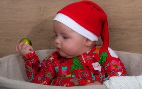 Ребенок в новогодней шапке с игрушкой в руке