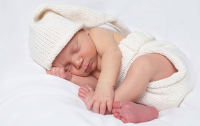 Нежный новорожденный ребенок в белом костюме