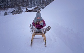 Девочка едет на санках с горки