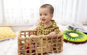 Маленький мальчик сидит в ящике в игровой комнате