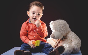 Little boy with a toy bear on a black background