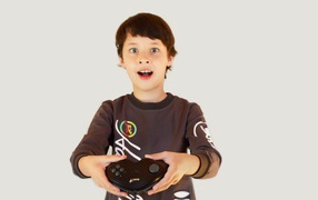 Маленький мальчик с приставкой на сером фоне 