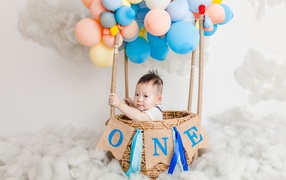 Маленький ребенок в корзине с шариками 