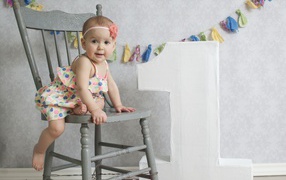 Маленькая девочка в платье на стуле