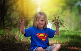 Маленькая девочка сидит на земле с травой