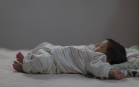 Маленький спящий грудной ребенок на кровати 