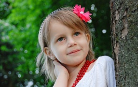Маленькая улыбающаяся девочка у дерева 