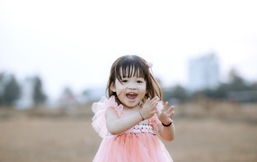 Довольная маленькая девочка в розовом платье 