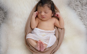 Спящий грудной ребенок на меховом покрывале 