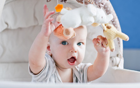 Маленький грудной ребенок в коляске с игрушками 