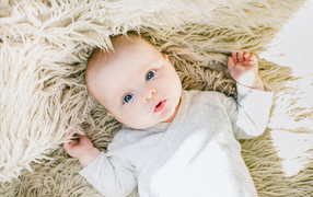 Маленький грудной ребенок на меховом покрывале 