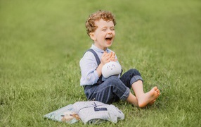 Улыбающийся мальчик сидит на траве