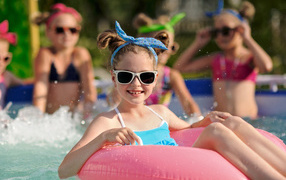 Улыбающаяся девочка со спасательным кругом в бассейне 