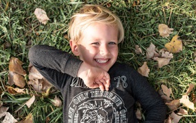 Улыбающийся маленький мальчик лежит на траве