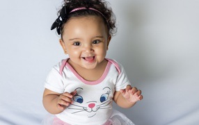 Улыбающаяся маленькая девочка на сером фоне 