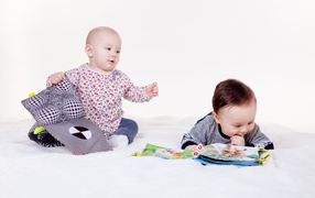 Два маленьких ребенка играют на белом фоне