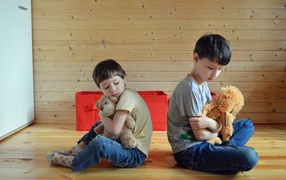 Два маленьких обиженных мальчика сидит на земле