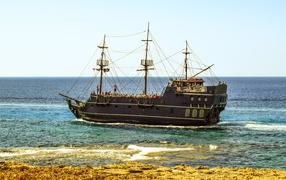 Большой черный пиратский корабль у берега