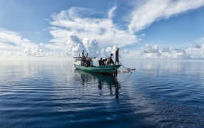Лодка с рыбаками в море с белыми облаками 