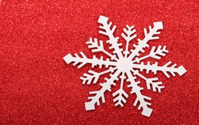 Белая бумажная снежинка на красном фоне 