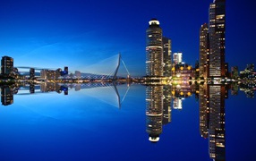 Небоскребы и мост отражаются в тихой воде