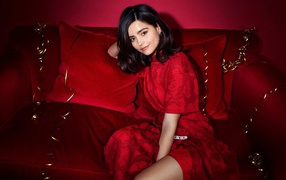 Красивая британская актриса Дженна Коулман сидит на красном диване