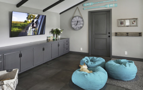 Голубые кресла в комнате с большим телевизором 