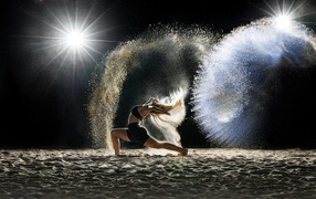 Девушка в черном костюме танцует на песке 