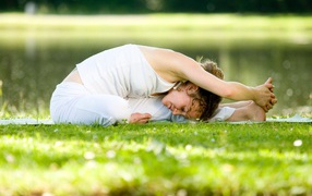 Girl in white suit doing yoga on the grass