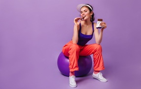 Girl with chocolate bar sitting on fitball