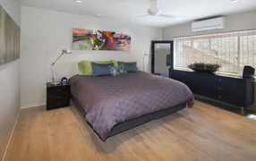 Большая серая кровать в спальне с белыми стенами