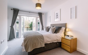 Большая высокая кровать в комнате с большим окном с балконом