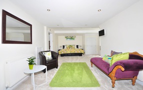 Большая гостиная с высокими белыми стенами и мебелью 