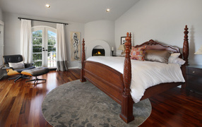 Большая деревянная кровать в спальне с камином 