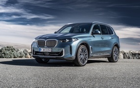 Автомобиль BMW X5 2023 на фоне грозового неба