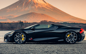 Черный автомобиль Bugatti W16 Mistral  на фоне горы