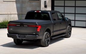 Черный пикап Ford F-150, 2024 года стоит у гаража