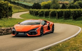 Оранжевый автомобиль Lamborghini Revuelto на дороге