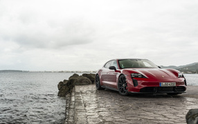 Красный автомобиль Porsche Taycan  у воды