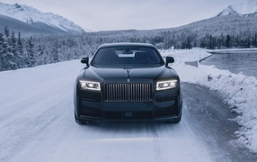 Черный автомобиль Rolls-Royce Black Badge Ghost  на зимней дороге