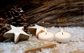 Две зажженные свечи, шишки и звезды