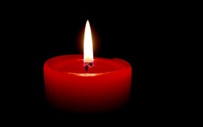 Burning red candle on a black background