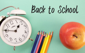 Colored pencils on a blue background with a clock and an apple