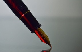 Золотое перо чернильной ручки на сером фоне